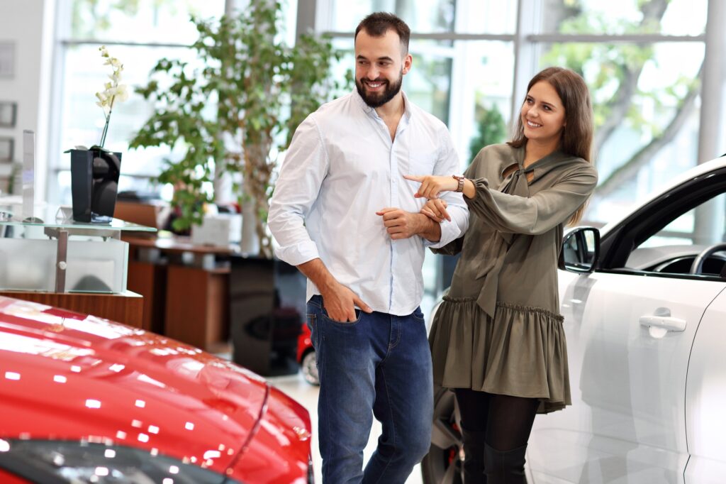 Adult couple choosing new car in showroom